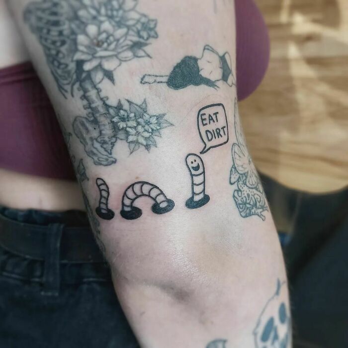 Funny tattoo of a worm saying "Eat Dirt" on an arm.