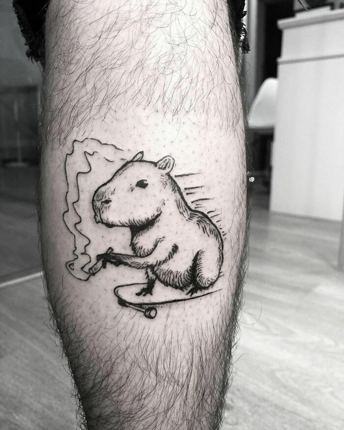 Funny tattoo of a capybara on a skateboard on a person's leg.