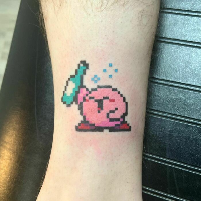 Funny tattoo of pink pixelated character on arm with a drinking bottle.
