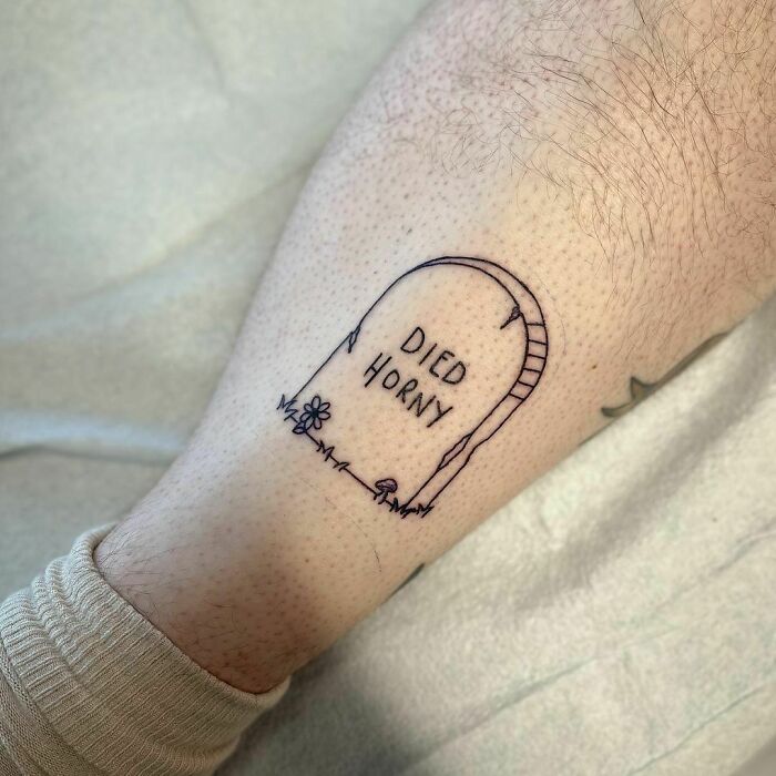 Funny tattoo on leg of a gravestone with "Died H***y" inscription.