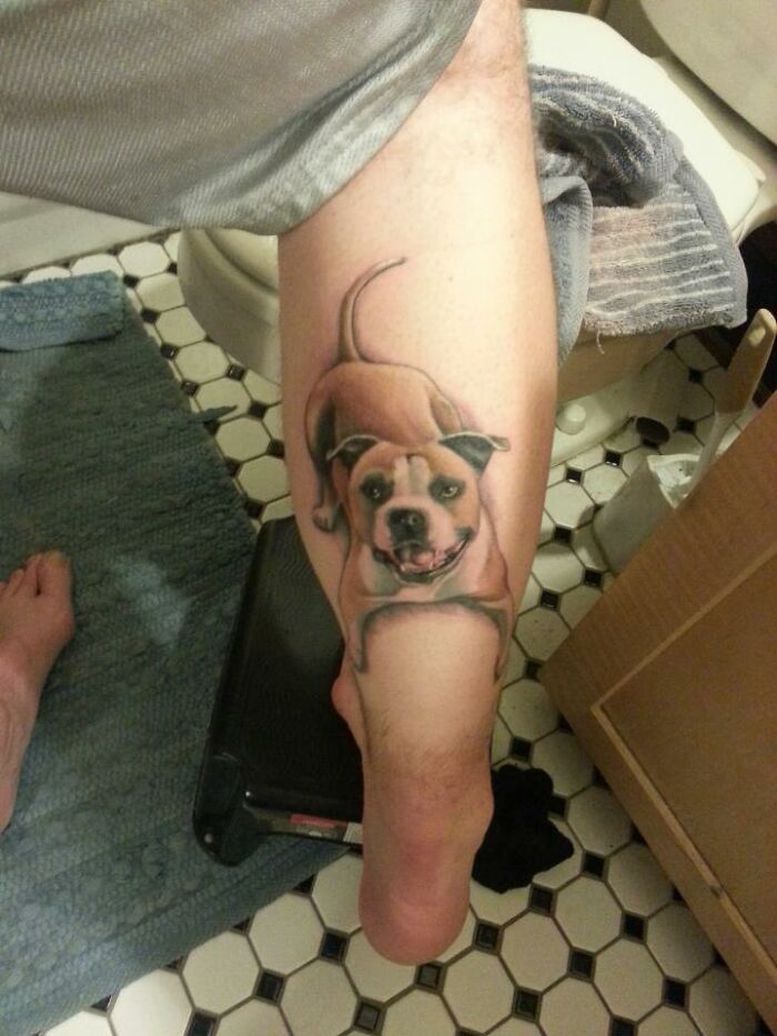 Tattoo of a smiling dog on a person's leg, showcasing pet-inspired body art.