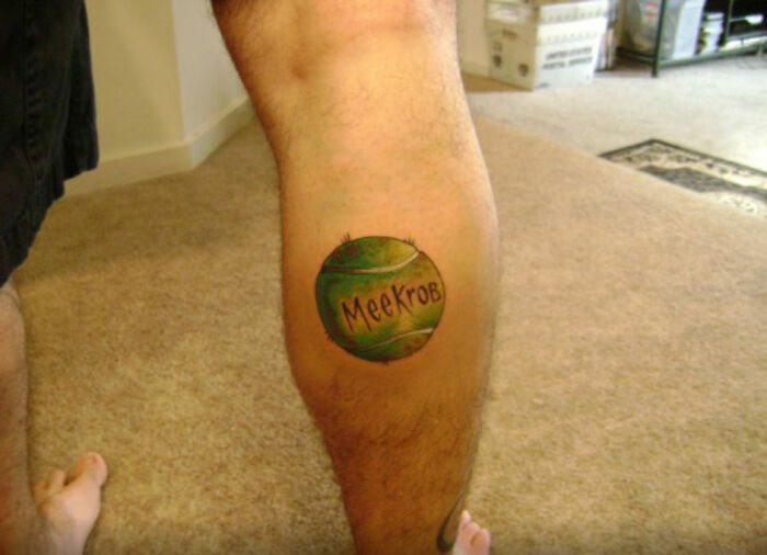 Tattoo of a green ball with "MeeKrob" on a person's leg, inspired by a pet.