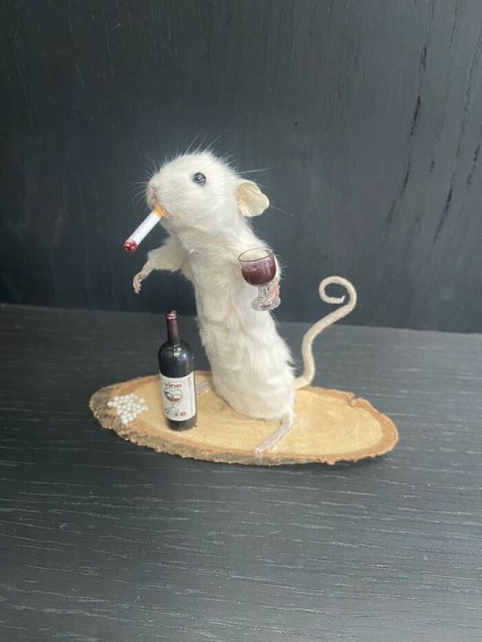 Bad taxidermy example with a mouse holding a wine glass and cigarette, next to a wine bottle.