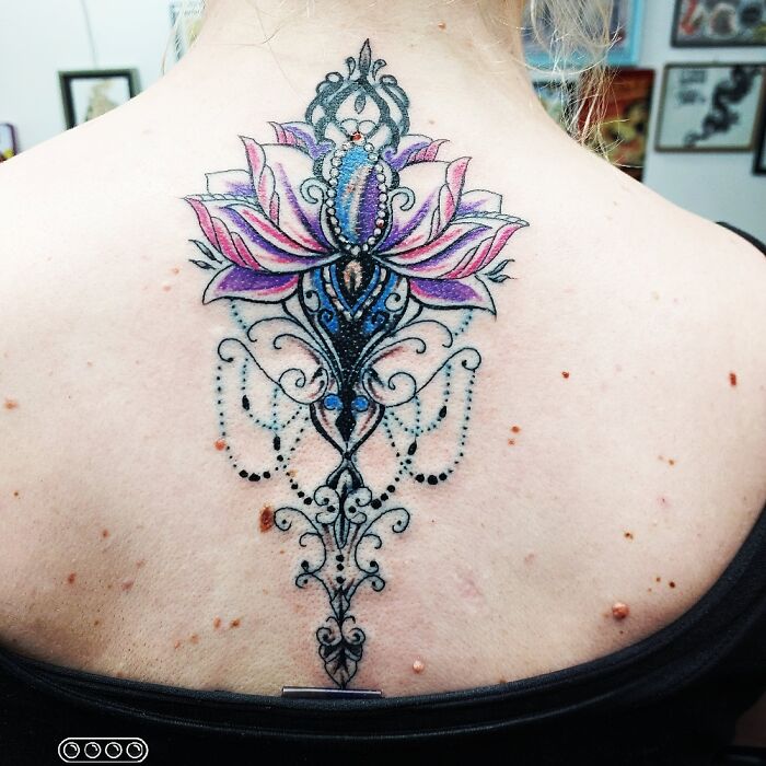 Colorful floral tattoo with intricate patterns displayed on a person's upper back.
