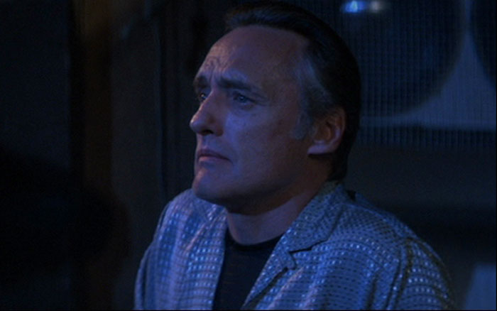 Dennis Hopper wearing a black t-shirt and patterned jacket in a dark scene from Blue Velvet, highlighting famous people married multiple times.