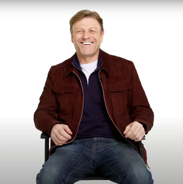 Sean Bean smiling in a dark red jacket and jeans, featured among famous people who got married multiple times.