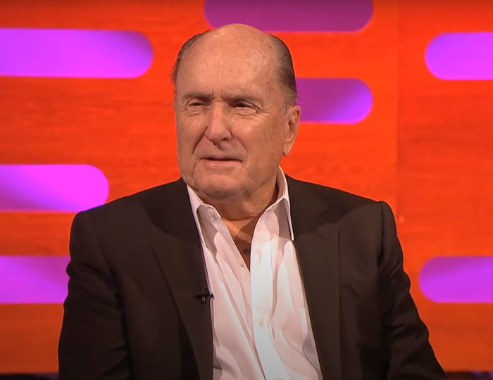 Robert Duvall wearing a black suit and white shirt, featured in famous people who got married multiple times.