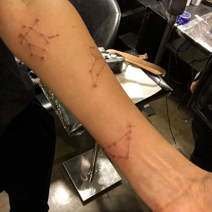 Celebrity tattoos of constellations on a forearm in a tattoo studio setting.
