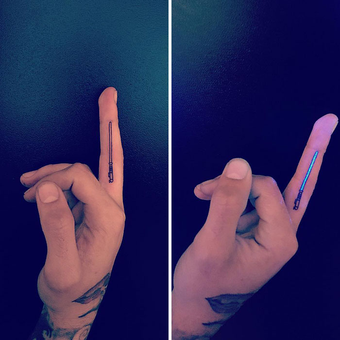 Finger tattoo of a lightsaber, glowing under UV light; a unique idea for a celebrity-inspired tattoo.