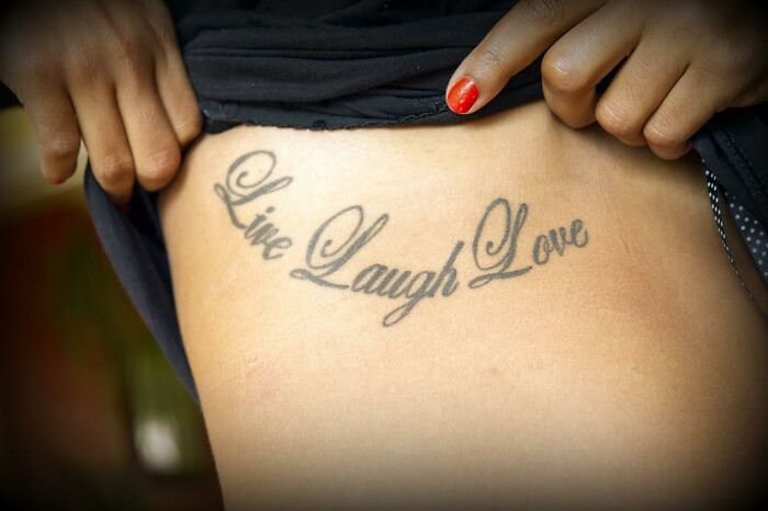 "Live Laugh Love tattoo on person's side, showing body art that some find less attractive."