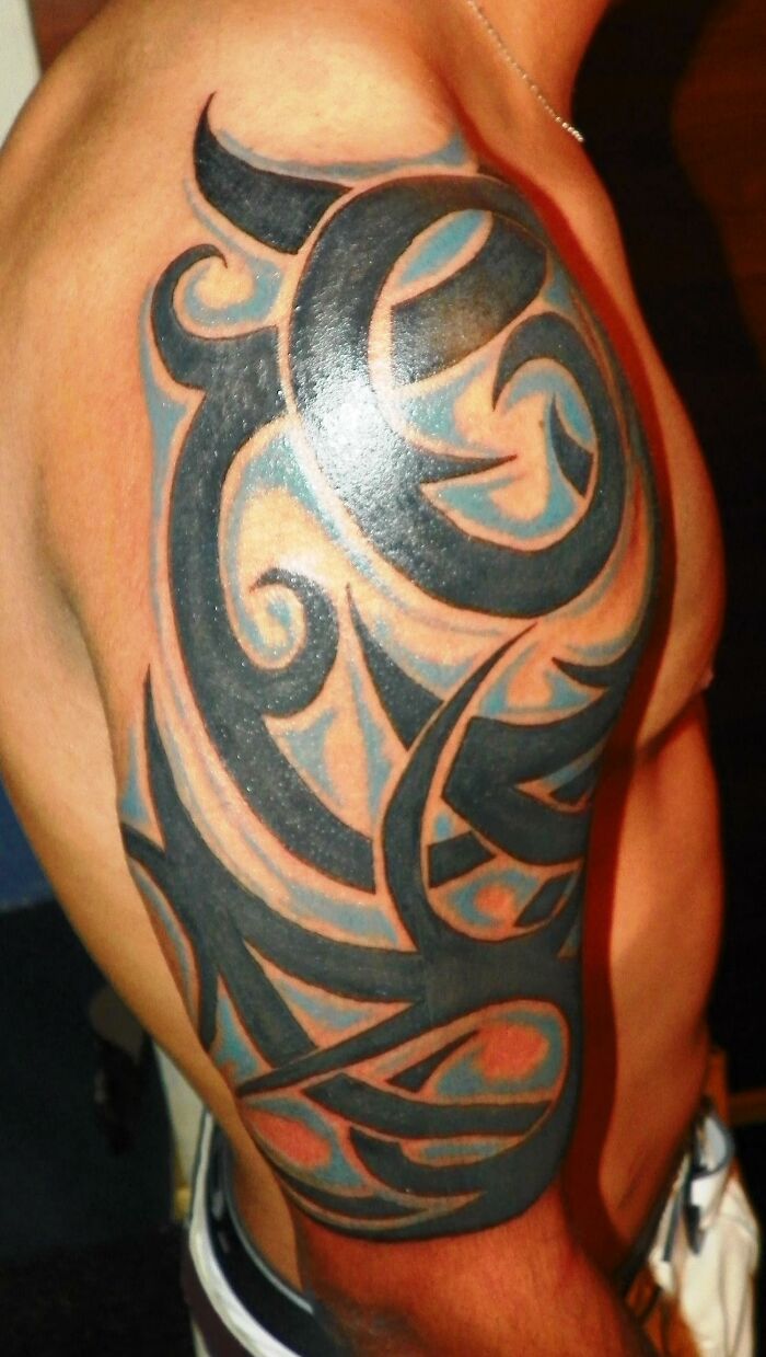 Arm displaying an intricate tribal tattoo design with bold black and orange colors.
