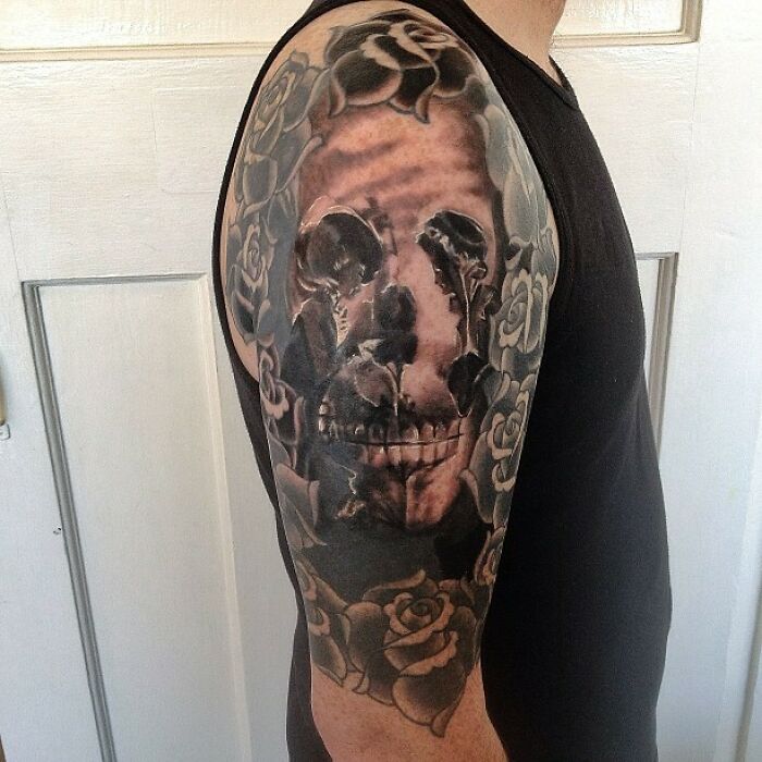 Optical illusion tattoo with roses and skull design on a person's arm.