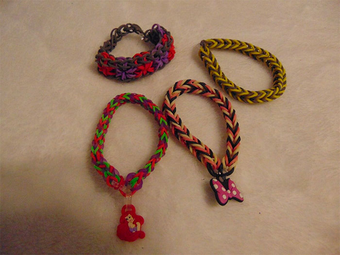 Colorful loom band bracelets with charms laid out on a surface, showcasing a popular nostalgic fashion trend.