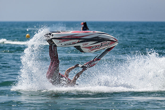 Person falling off a jet ski performing a flip on the water, showcasing big trends in water sports activities.