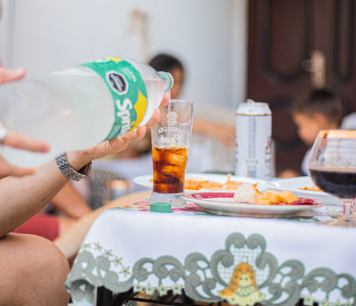 Person pouring soda into a glass at a table with snacks and drinks, illustrating big trends in casual social gatherings.