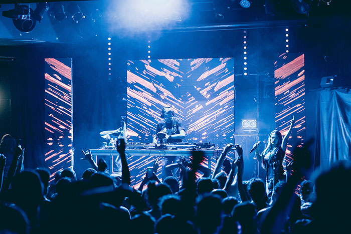 DJ performing on stage with a crowd dancing and colorful lights showing big trends in music forgotten over time