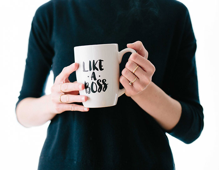 Person wearing black holding white mug with like a boss text, illustrating big trends people almost forgot existed.