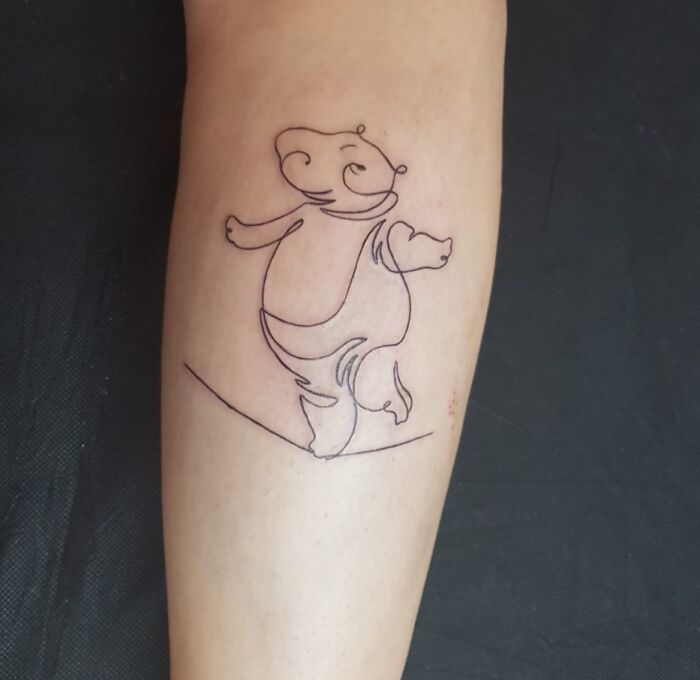 Minimalist hippo tattoo design on a forearm, featuring a simple line art style.