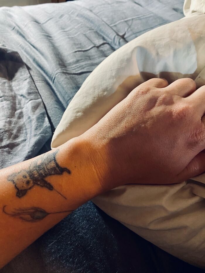 Close-up of a tattoo featuring a small bear on a person's forearm resting on a pillow.
