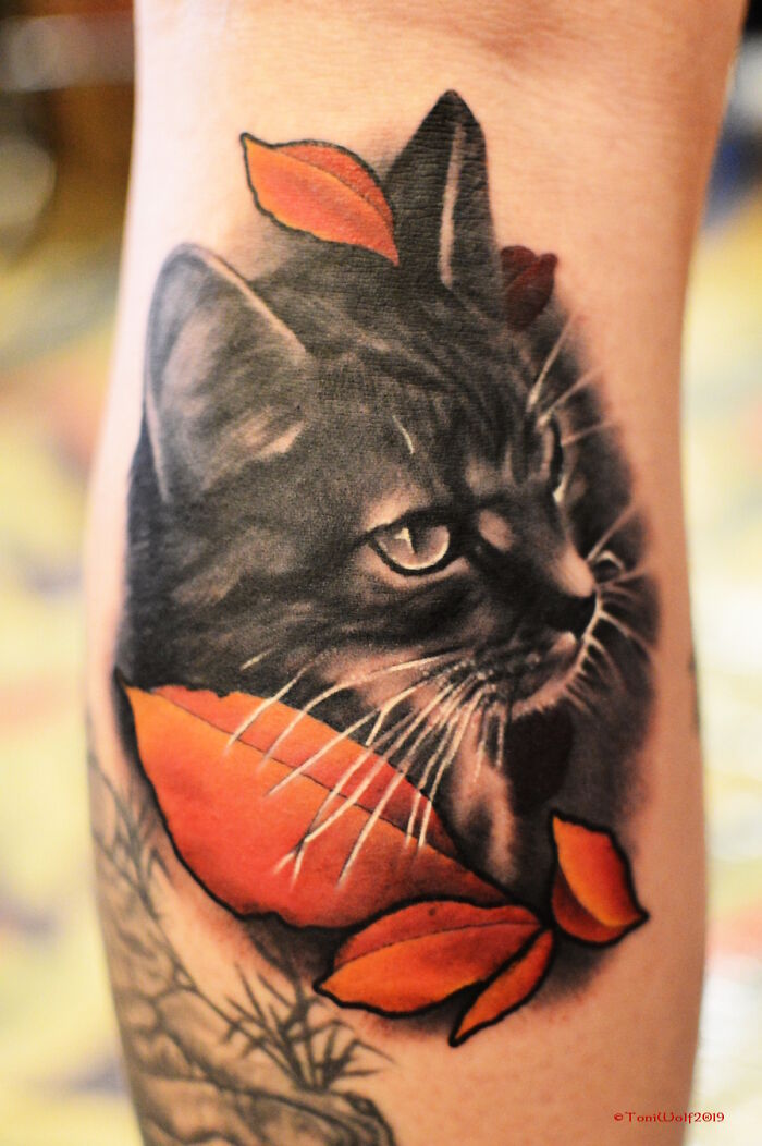 Pet tattoo of a cat with orange leaves, showcasing detailed and lifelike art.