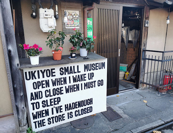 Small Japanese museum entrance with a humorous sign showcasing unique cultural inventions and traditions.