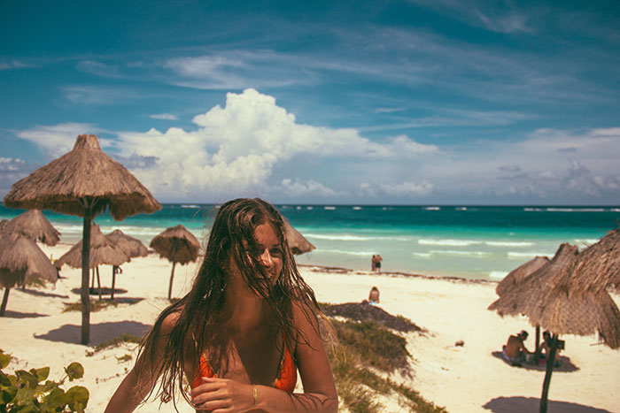 Woman enjoy exotic landscape with beach and straw umbrellas