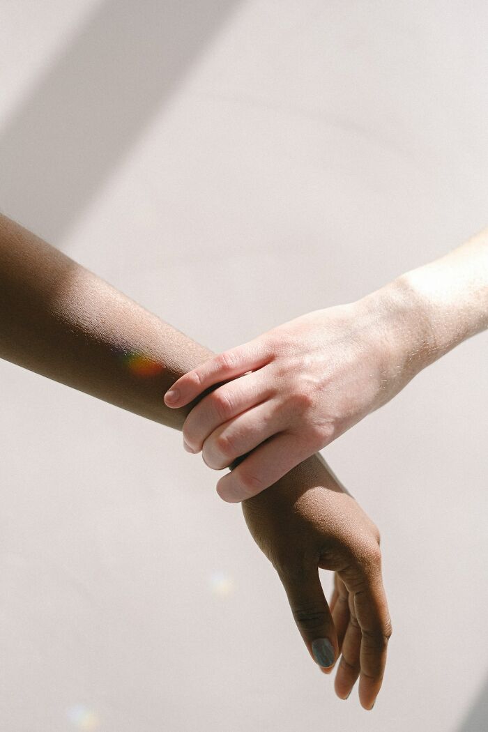 Two hands of different skin tones gently holding each other, symbolizing good intentions and connection.