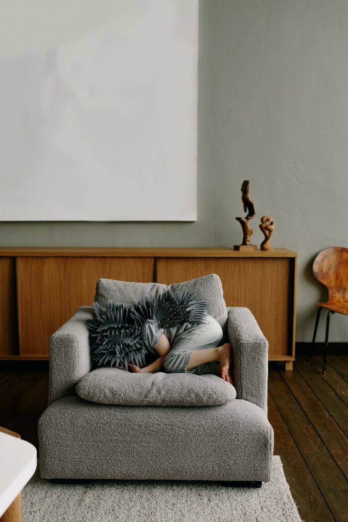Child curled up on a grey armchair in a minimalist room, illustrating good intentions that ended badly concept.