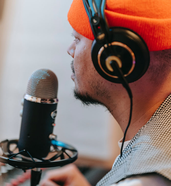 Man wearing headphones and an orange hat speaking into a microphone about professions that may soon disappear.