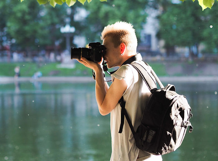 Person with a stylish haircut taking photos by a lake, representing professions that may soon disappear.