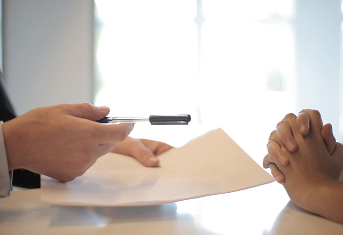 Two people in a meeting, one holding a pen and documents, discussing professions that may soon disappear.