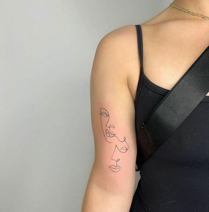 Minimalist line tattoo of a face on a person's arm, showcasing unique line art design.