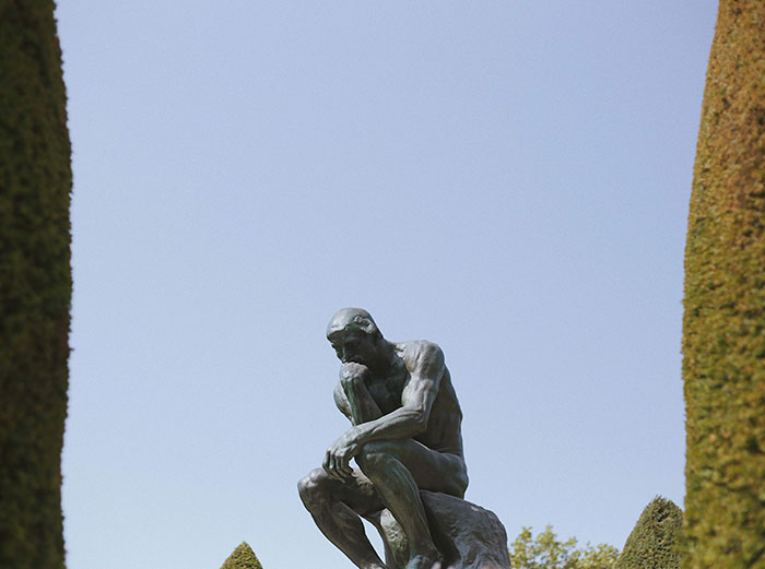 Statue of a man deep in thought outdoors, symbolizing contemplation and ideas behind texting games.