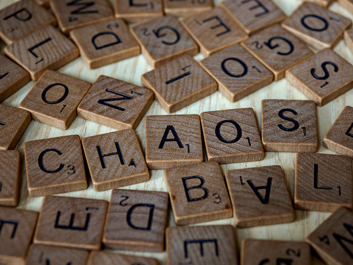 Wooden letter tiles scattered on a table with the word chaos spelled out, representing texting games ideas.