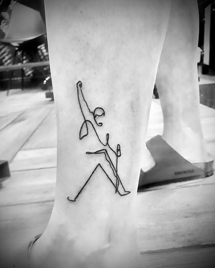 Minimalist single-line tattoo depicting a person rock climbing on a leg.