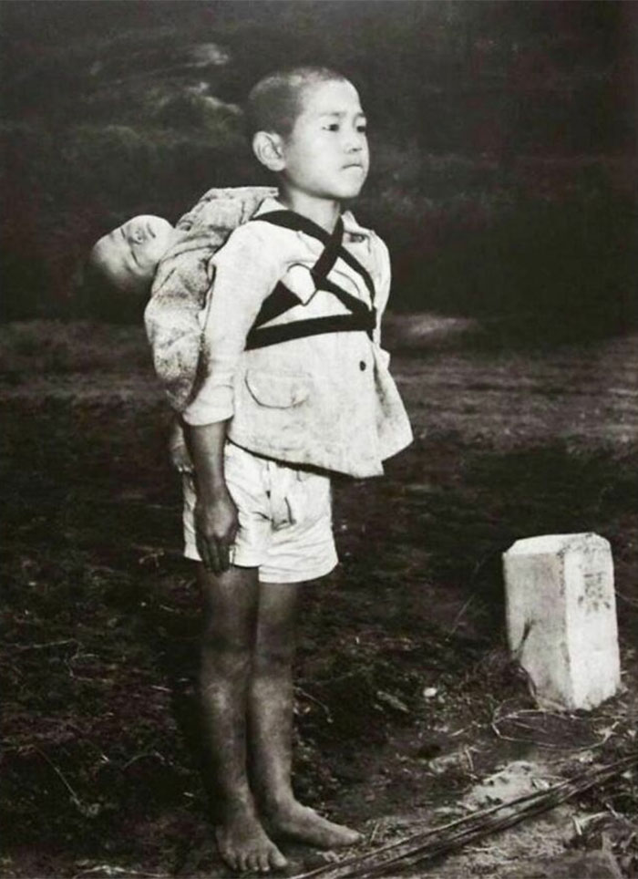 1945. 10-Year-Old Stoic Japanese Boy Standing At Attention Having Brought His Dead Younger Brother To A Cremation Pyre, Nagasaki