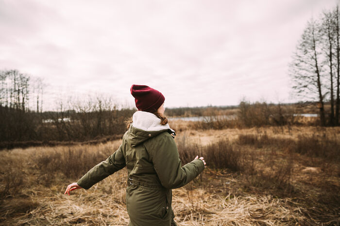 Person in a green jacket and red hat walking in a field on a cloudy day, representing common myths misconceptions.
