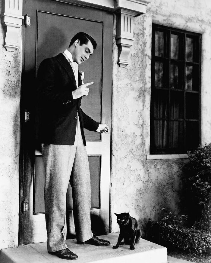 Between Scenes Of The Movie "Kiss And Make-Up" (1934), American-British Heartthrob Cary Grant Was Photographed With A Black Kitten