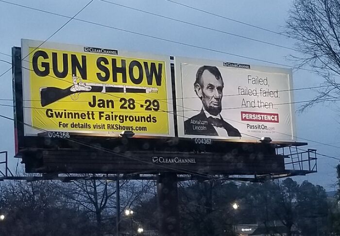 Billboard showing a gun show ad next to an Abraham Lincoln persistence sign, an example of hilariously absurd signs.