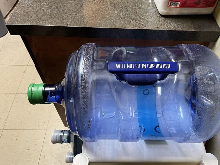 Large water jug labeled will not fit in cup holder, showcasing one of the hilariously absurd signs shared online.