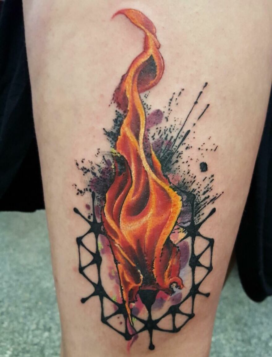 Watercolor tattoo featuring a vibrant flame with splash effects and geometric elements.