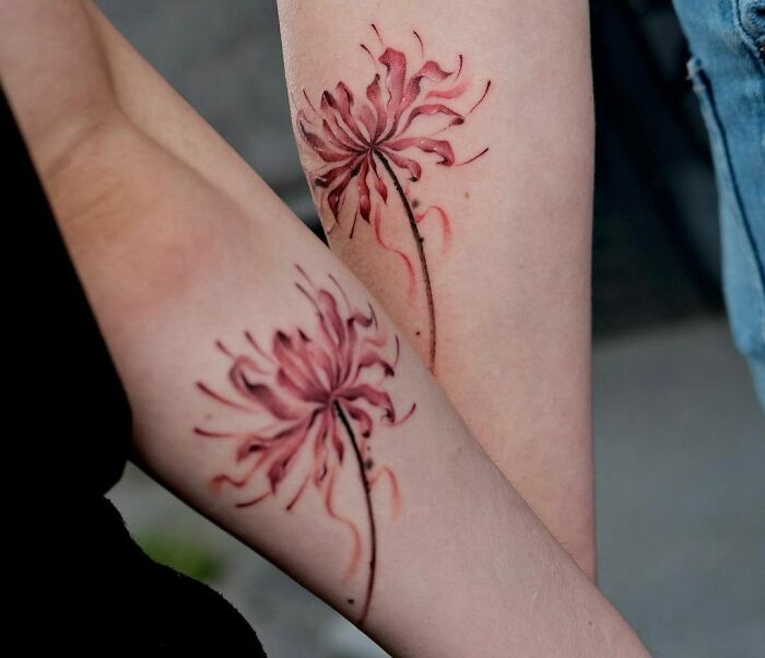 Matching brother and sister tattoos featuring a delicate pink flower design on forearms.