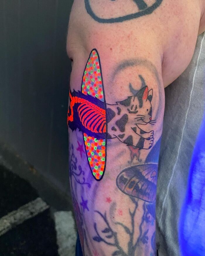 Tattoo of a psychedelic cat with vibrant colors and patterns on an arm.