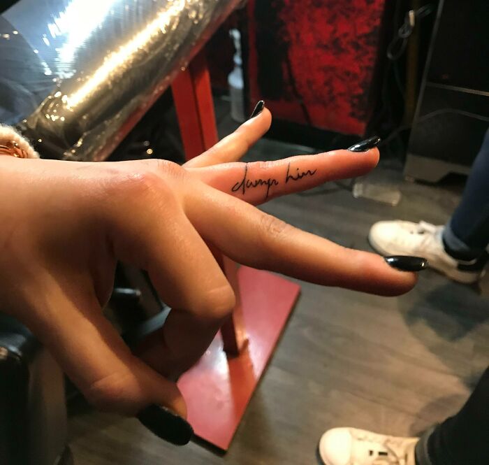 Funny finger tattoo with script text on a person's index finger.