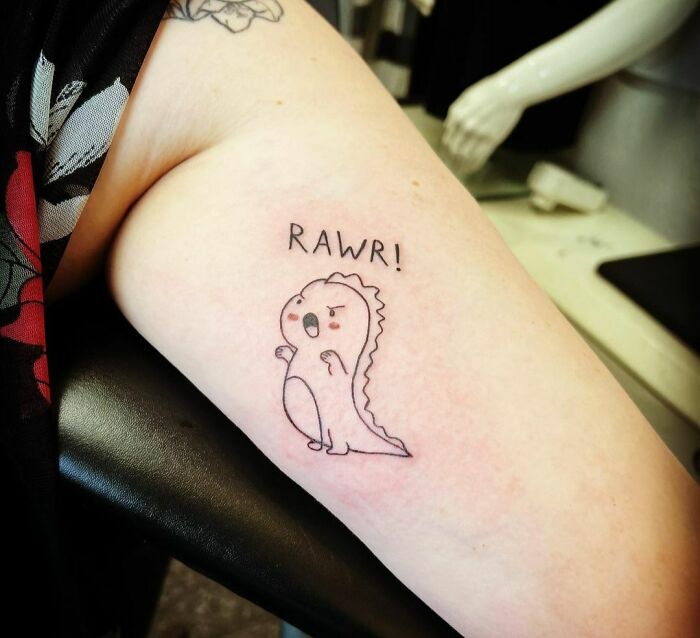 Funny dinosaur tattoo on arm with "RAWR!" text, showcasing humorous tattoo art.