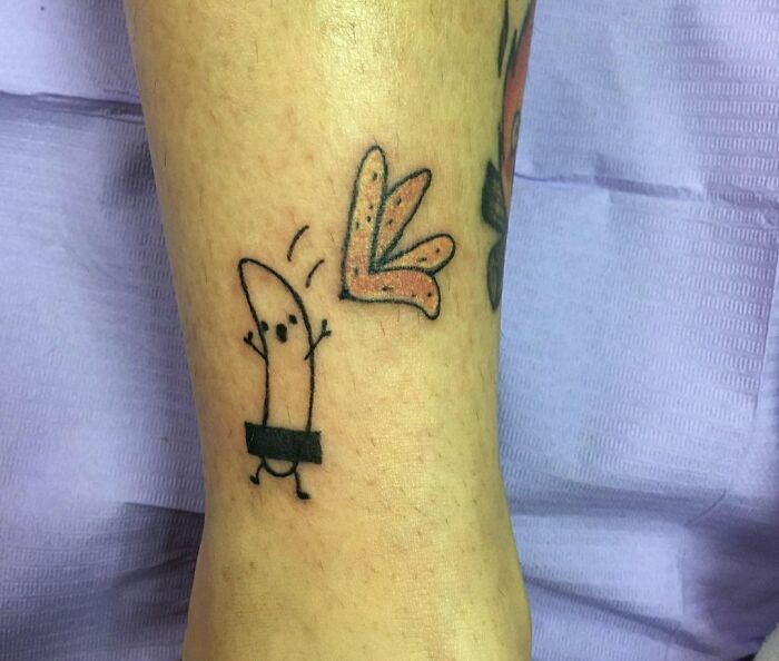 Funny tattoo of a cartoon banana with censor bar on leg, featuring playful design.