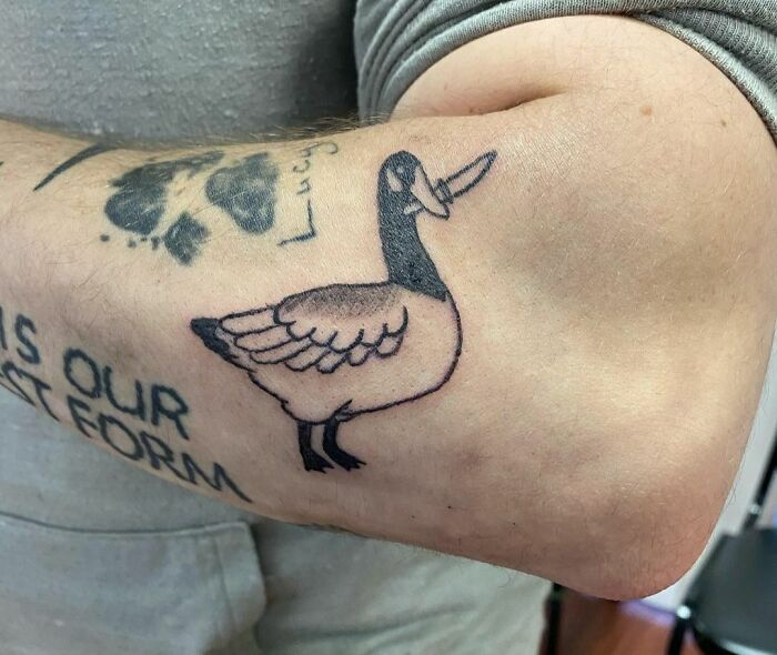 Funny goose with a knife tattoo on a forearm, showcasing humorous body art.