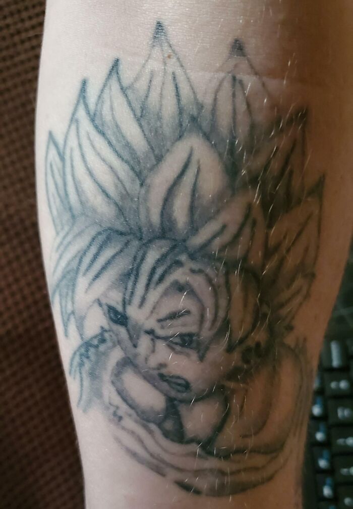 Funny tattoo of Goku with exaggerated features on an arm, showcasing humor and creativity in tattoo art.