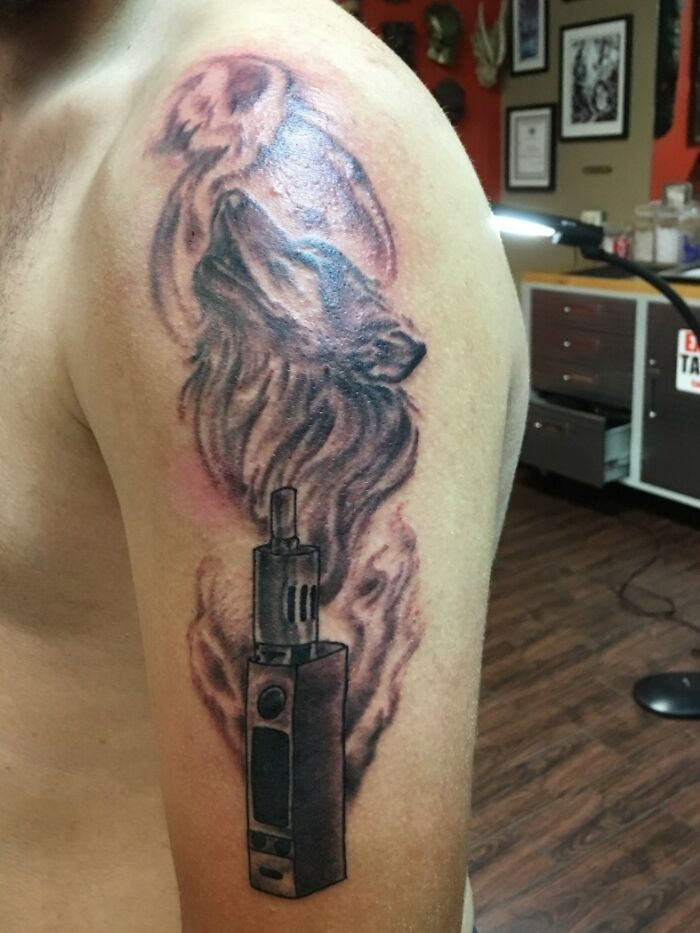 Vapor wolf arm tattoo showcasing funny and creative art, featuring smoke forming a wolf above a vaping device.
