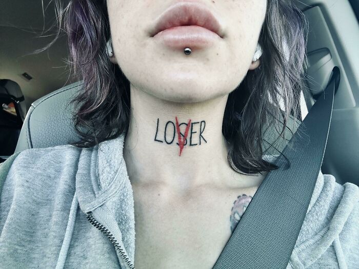Neck tattoo with "LOVER" altered from "LOSER" in creative word tattoo design.